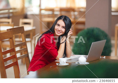 Young woman with phone and laptop sitting in the 23646655