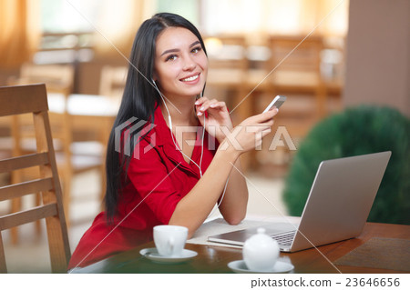 Young woman with phone and laptop sitting in the 23646656