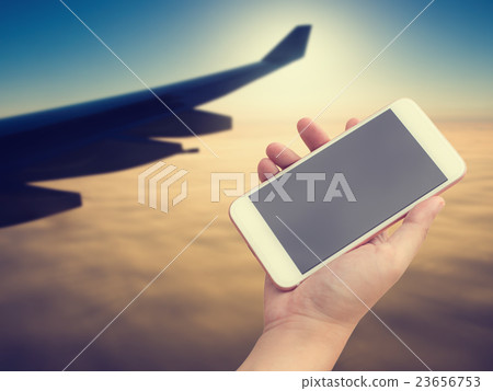 Hand using smartphone on aircraft wing background. Hand using smartphone on aircraft wing background. 23656753