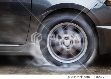 Car racing spinning wheel burns rubber on floor. 23657788