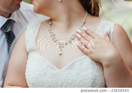 the fat bride wears a necklace around his neck 23658543