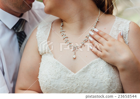 the fat bride wears a necklace around his neck 23658544