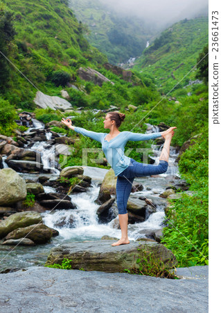 Woman doing yoga asana Natarajasana outdoors at 23661473