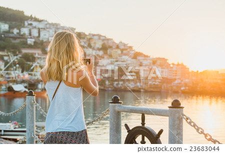 Young blond tourist woman making photo of sunset Young blond tourist woman making photo of sunset 23683044