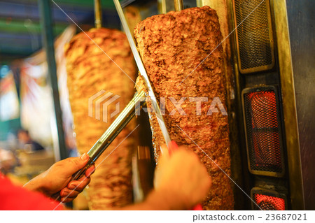 chef's arm moving to cut Kebab meat 23687021