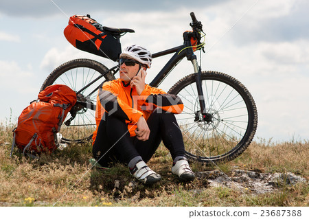Young Cyclist In Orange Shirt Checks His Phone 23687388