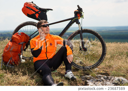 Young Cyclist In Orange Shirt Checks His Phone Young Cyclist In Orange Shirt Checks His Phone 23687389