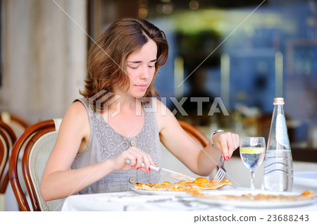 Young woman eating italian pizza in outdoors restaurant 23688243