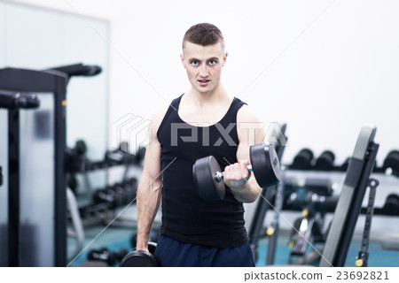 Athletic man with a dumbells in gym Athletic man with a dumbells in gym 23692821