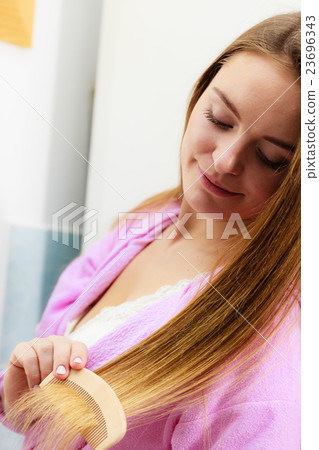 Woman combing her long hair in bathroom 23696343