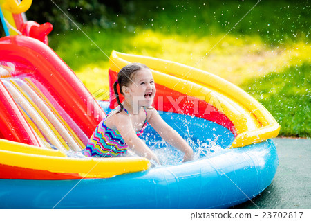 Little girl in garden swimming pool Little girl in garden swimming pool 23702817