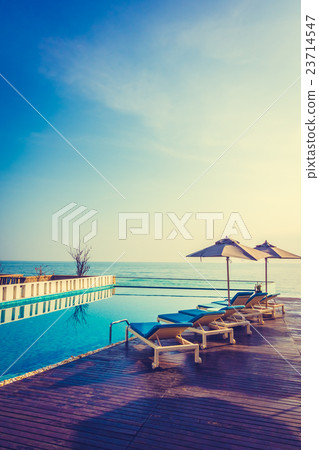 Umbrella and chair around swimming pool 23714547