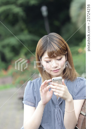 一位攜帶手機的年輕女士 一位攜帶手機的年輕女士 23724256