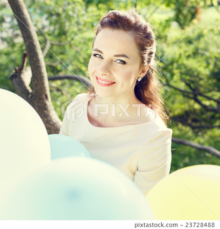 young woman with balloons sitting on tree 23728488