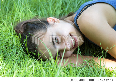 portrait of a laughing teenage girl laying in the grass 23733673