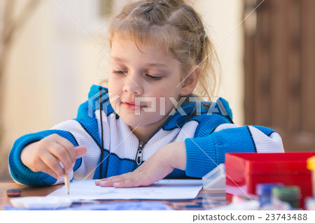 Pretty girls sitting at a table in the courtyard of the house and draws pencil 23743488