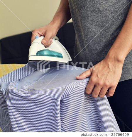 young man ironing a shirt 23766409