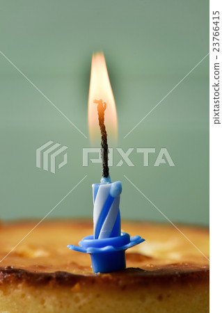 lit birthday candle on a cheesecake 23766415