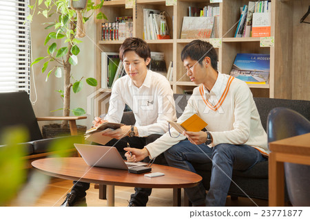 兩個男人坐在共享辦公室的沙發上，彼此見面 23771877