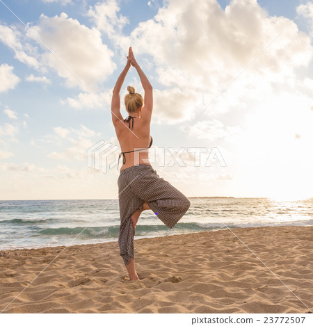 Woman practicing yoga on sea beach at sunset. 23772507