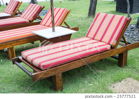 Wooden sunbed with mattress in the garden. 23777521