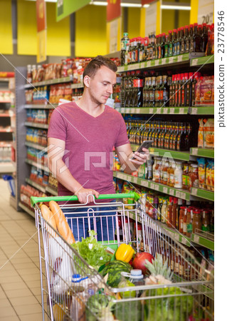 Young man using mobile phone in supermarket 23778546