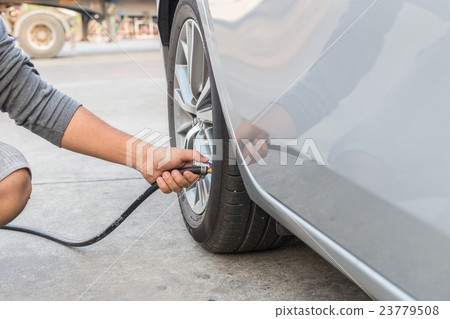 Man checking air pressure and filling air to the tires of his car 23779508