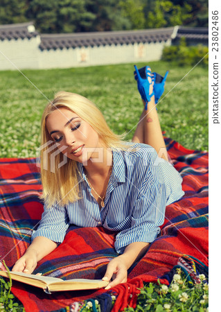 Beautiful young woman lying on green grass outdoor Beautiful young woman lying on green grass outdoor 23802486