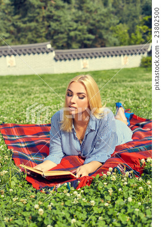 Beautiful smiling woman lying on a grass outdoor Beautiful smiling woman lying on a grass outdoor 23802500