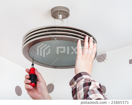 Electrician repairs round ceiling light Electrician repairs round ceiling light 23805571
