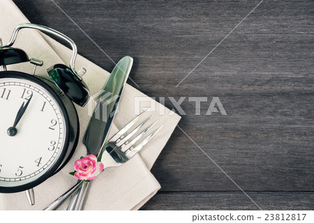 Alarm clock and silverware with a flower on wood Alarm clock and silverware with a flower on wood 23812817