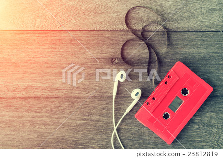 Red cassette tape with earphone over wooden table Red cassette tape with earphone over wooden table 23812819