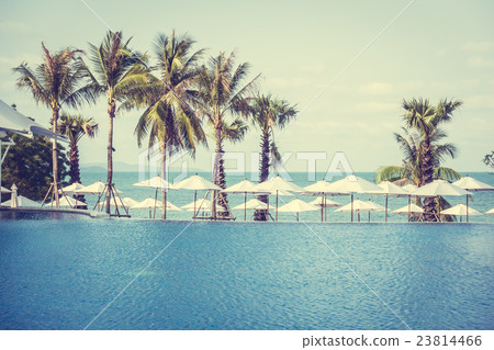 Umbrella and chair around swimming pool 23814466