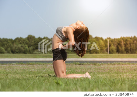 Young skinny girl does exercise on the grass. 23840974