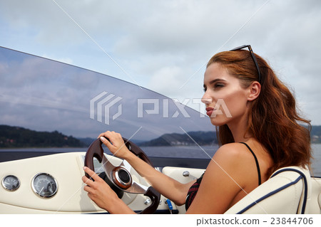 Summer vacation - young woman driving a motor boat Summer vacation - young woman driving a motor boat 23844706