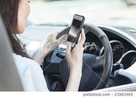 駕駛的婦女,當觀看智能手機時 駕駛的婦女,當觀看智能手機時 23863469