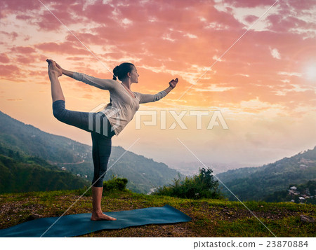 Woman doing yoga asana Natarajasana outdoors at 23870884