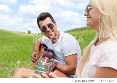 Young man playing guitar to his girl summer day Young man playing guitar to his girl summer day 23872588