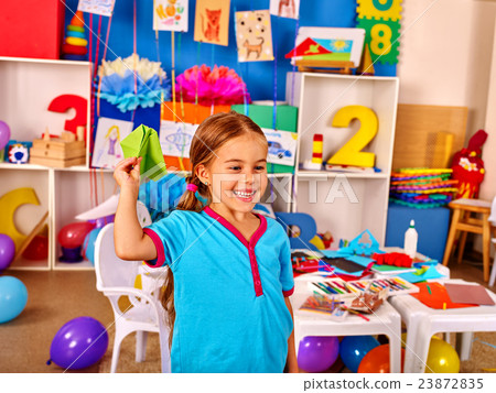 Girl keeps origami airplane in primary school. 23872835