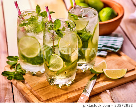 On wooden boards is glasses with mohito and knife. On wooden boards is glasses with mohito and knife. 23872958
