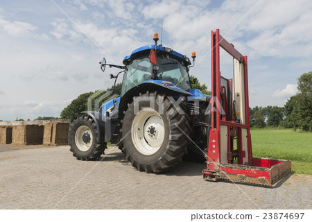 Blue tractor with a red bale slicer. 23874697