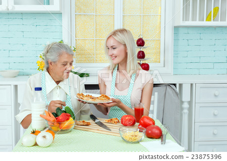 Girl feeds the grandmother with food. Girl feeds the grandmother with food. 23875396