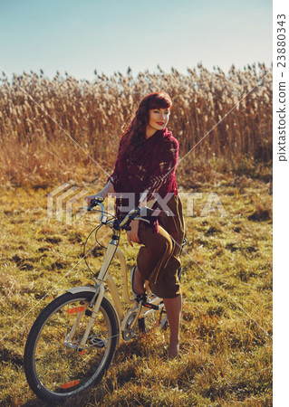 Pretty girl riding bicycle in field 23880343