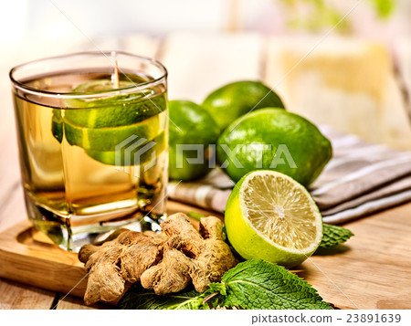 Glass with green transparent lime drink and ginger 23891639