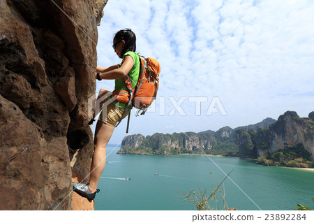 young woman rock climber climbing at seaside cliff 23892284