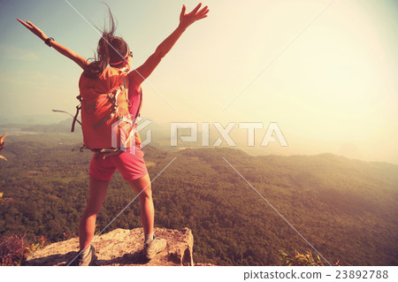 cheering young  woman open arms on mountain peak  23892788