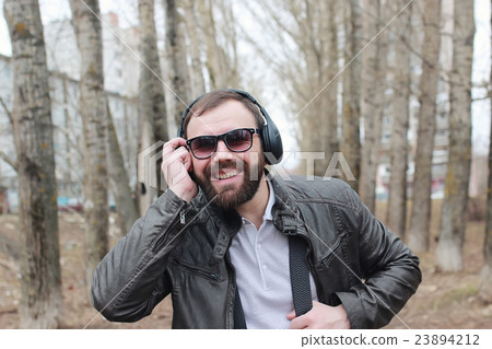 man with beard and headphones in the park 23894212