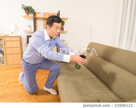 噴灑防臭劑的一個人在沙發 噴灑防臭劑的一個人在沙發 23896122