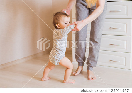 baby taking first steps with mother help 23911997
