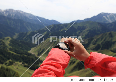 young woman hiker checking the altimeter on sports watch at mountain peak 23912406
